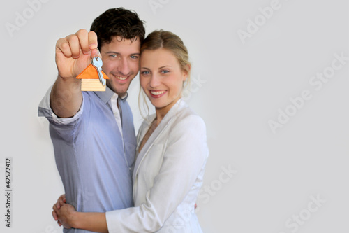 Photo: Young smiling couple holding keys of their new house Young smiling couple holding keys of their new house