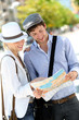 Trendy young couple in town with touristic map