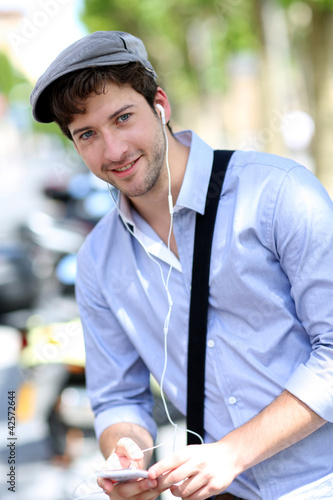 Photo: Young trendy guy talking on mobilephone in the street Young trendy guy talking on mobilephone in the street