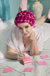 Portrait of young woman lying on bed while writing on sticky notepads
