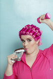 Photo: Portrait of young woman licking chocolate bar while light dumbbell over colored background Portrait of young woman licking chocolate bar while light dumbbell over colored background
