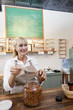 Happy senior female filling jar with scoop while looking away in store