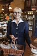 Photo: Portrait of a happy senior owner standing with basket full of spices in store Portrait of a happy senior owner standing with basket full of spices in store