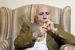 Mature man igniting cigar while sitting on armchair
