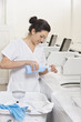 Happy young female employee pouring detergent in washing machine Laundromat
