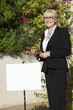 Photo: Happy senior woman standing by sign board with clipboard Happy senior woman standing by sign board with clipboard