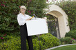 Photo: Portrait of a happy senior female agent hammering sign board in lawn Portrait of a happy senior female agent hammering sign board in lawn