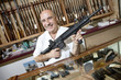 Foto: Portrait of a happy mature merchant with rifle in gun shop Portrait of a happy mature merchant with rifle in gun shop