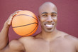 Photo: Portrait of a young African American man with basketball on shoulder over colored background Portrait of a young African American man with basketball on shoulder over colored background