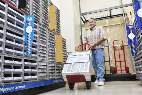 Photo: Mature man pushing handtruck in hardware store Mature man pushing handtruck in hardware store