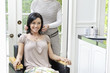 Happy beautiful mid adult woman with hairstylist in background