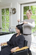 Cheerful hairstylist giving a haircut to beautiful mid adult woman in beauty salon
