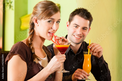 Photo: Young couple drinking cocktails in bar or restaurant Young couple drinking cocktails in bar or restaurant