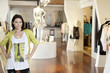 Foto: Portrait of a happy mid adult woman standing with hands on hips in fashion clothing store Portrait of a happy mid adult woman standing with hands on hips in fashion clothing store
