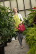 Young woman with watering can in greenhouse