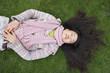 Top view of young Asian woman with long black hair lying on lawn