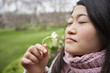 Close-up of a young Asian woman smelling flower in park