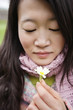 Close-up of a young Asian woman looking at flower