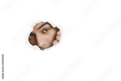 Foto: Portrait of a young Asian male peeking from paper hole Portrait of a young Asian male peeking from paper hole