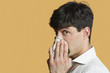 Portrait of a man blowing his nose over colored background