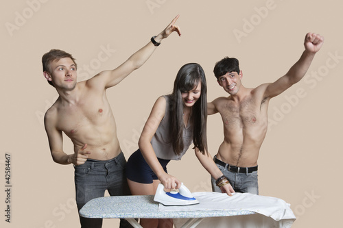 Photo: Shirtless men with woman ironing shirt over colored background Shirtless men with woman ironing shirt over colored background