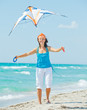 Woman on beach playing with a colorful kite