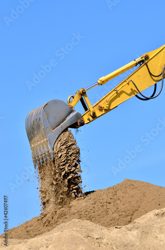 Photo: new yellow excavator working on sand dunes. Scoop close-up new yellow excavator working on sand dunes. Scoop close-up