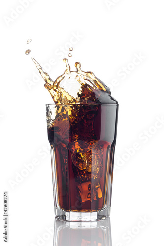 Photo: splash in glass of cola with ice cubes splash in glass of cola with ice cubes