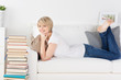 frau mit einem stapel bücher auf dem sofa