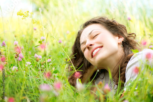 Photo: Beautiful Young Woman lying in Meadow of Flowers. Enjoy Nature Beautiful Young Woman lying in Meadow of Flowers. Enjoy Nature
