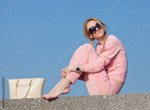 Photo: Girl in sunglasses with bag on background of sky Girl in sunglasses with bag on background of sky