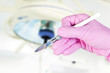 scalpel in surgeon's hand under lamp