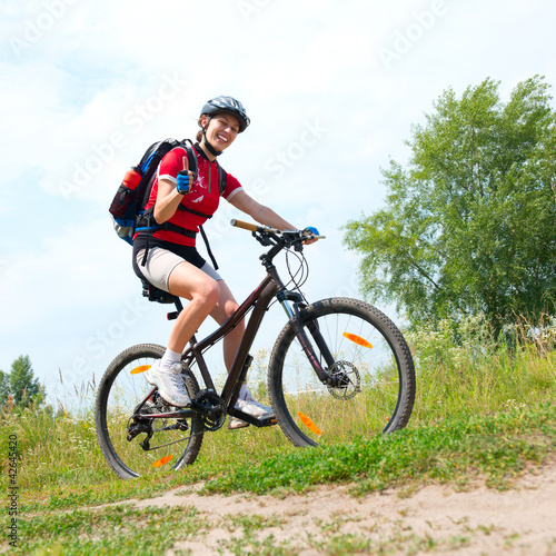 Photo: Happy Young Woman riding bicycle outside. Healthy Lifestyle Happy Young Woman riding bicycle outside. Healthy Lifestyle