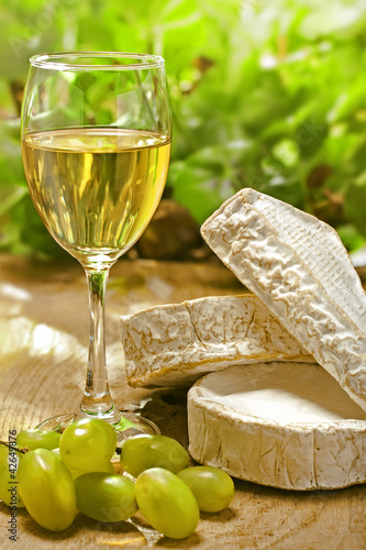 Foto: White wine, Brie, Camembert and grape on the table outdoor White wine, Brie, Camembert and grape on the table outdoor
