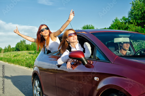 Photo: Two pretty happy girls in the car. Concept of carefree roadtrip Two pretty happy girls in the car. Concept of carefree roadtrip