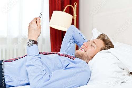 Foto: mann mit handy auf dem bett mann mit handy auf dem bett