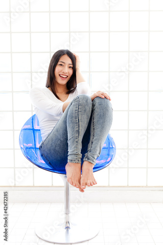 Photo: a young asian woman sitting on blue chair a young asian woman sitting on blue chair