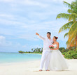 A bride holding a bouquet and groom looking towards, shot on a b