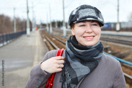 Photo: Attractive woman in cap standing on railway station Attractive woman in cap standing on railway station