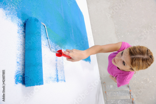 Photo: happy smiling woman painting interior of house happy smiling woman painting interior of house