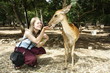 Young Caucasian girl feeding a deer in a park