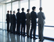 Photo: Business people standing in a row and looking out window Business people standing in a row and looking out window