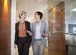 Businesswomen talking and walking in office corridor