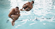 Men doing cannonball dives into swimming pool