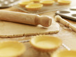 Rolling pin on dough surrounded by puff pastry tarts