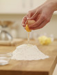 Woman cracking egg over flour nest