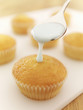 Spoon of icing dripping on cupcake