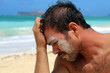 young man with sand on face by beach