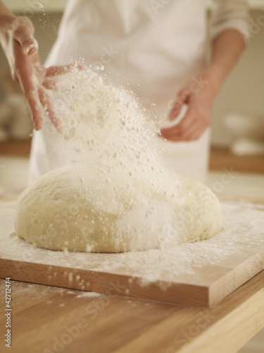 Photo: Woman dusting dough with flour Woman dusting dough with flour