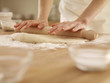 Woman pressing dough with rolling pin